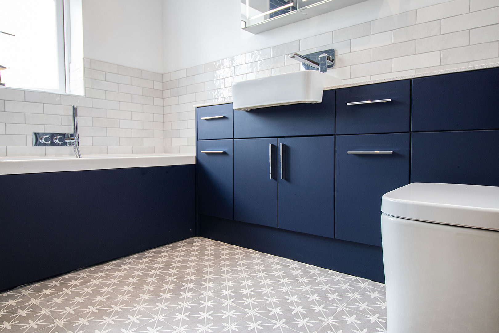 A well-designed bathroom showcasing blue cabinets and a white toilet